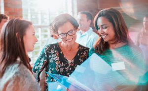 a group of women looking at a folder